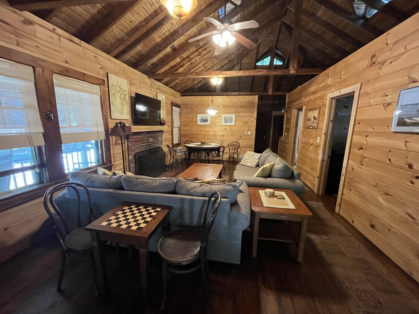 Large living room with fireplace and game table inside Clubhouse Cottage