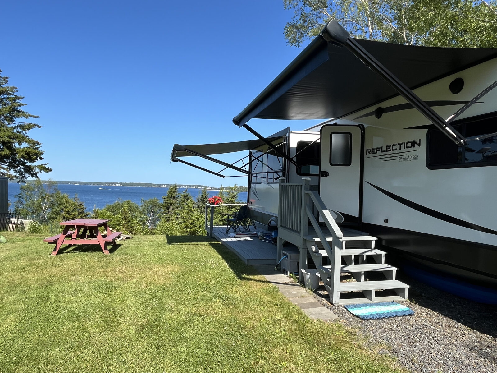 Fifth-wheel camper on an oceanfront site with a picnic table overlooking the bay