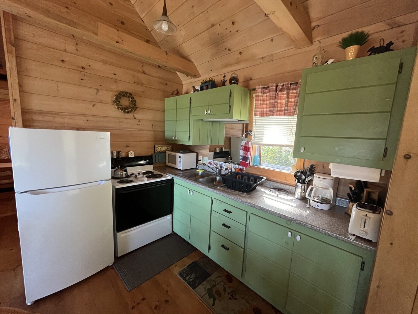 Full kitchen with green cabinetry inside Outer Heron Cottage